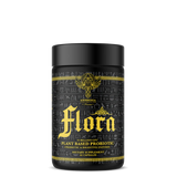 A black cylindrical container with gold and yellow text and graphics, labeling it 'Flora' as a Plant-Based Probiotic dietary supplement.